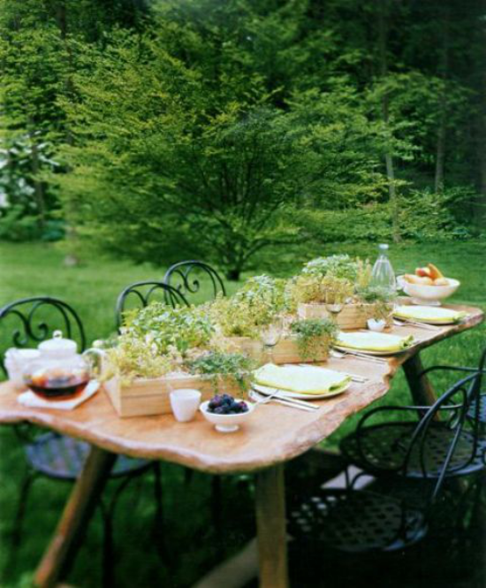 Essecke im Grünen alter Tisch sehr interessante Form Stühle serviert dekoriert Holzkästen mit grünen Kräutern