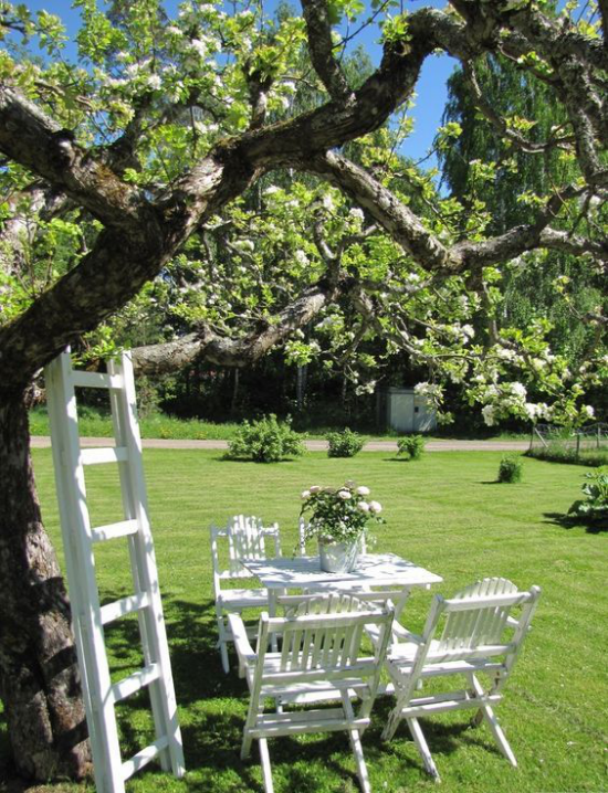 Essecke im Grünen unter einem Baum weiße Möbel Tisch Stühle Leiter schöne Wiese