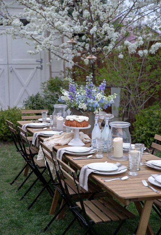 Essecke im Grünen unter einem blühenden Baum gedeckter Tisch für mehrere Personen Vase mit schönen Blumen