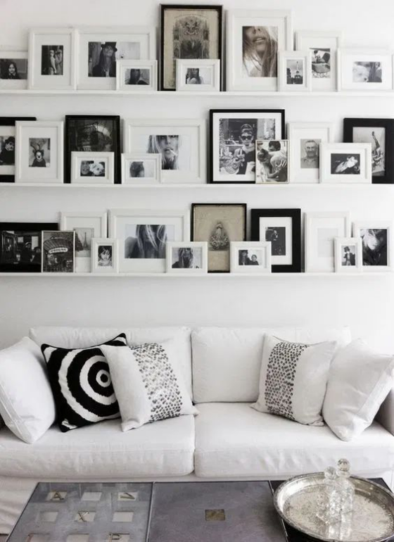 Fotowand auf Leisten weißes Sofa Deko Kissen weiße leisten zahlreiche Fotos in schwarzen und weißen Rahmen