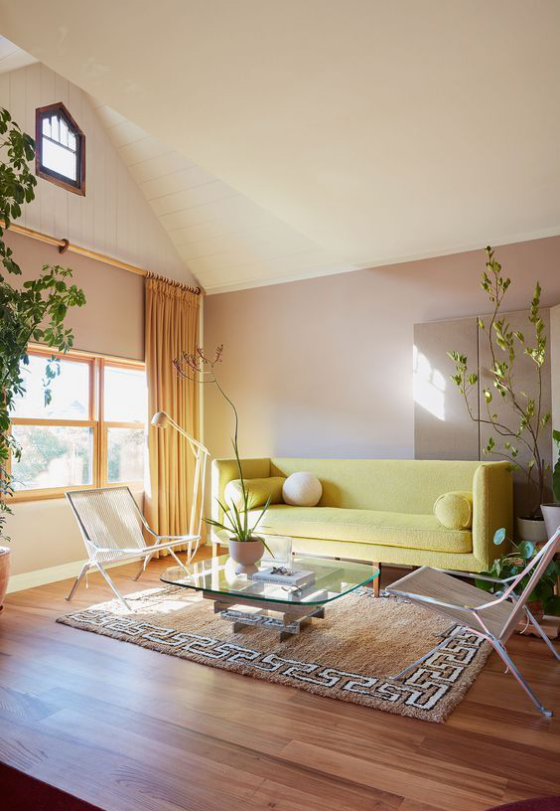 Gelbes Sofa Zitronengelb helles Wohnzimmer schick eingerichtet Glastisch Teppich zwei moderne Sessel Gardinen grüne Zimmerpflanzen