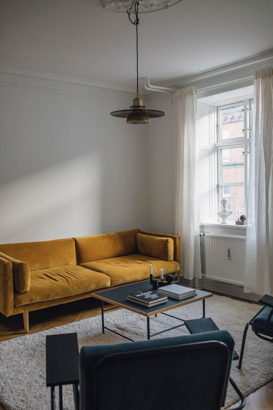 Gelbes Sofa als Blickfang minimalistisches Wohnzimmer grau schwarz als dominierende Farben kleiner Tisch Bücher
