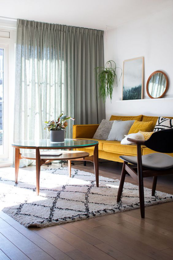 Gelbes Sofa in Goldgelb Wurfkissen sehr ansprechendes Wohnambiente leichte Gardinen Teppich runder Tisch