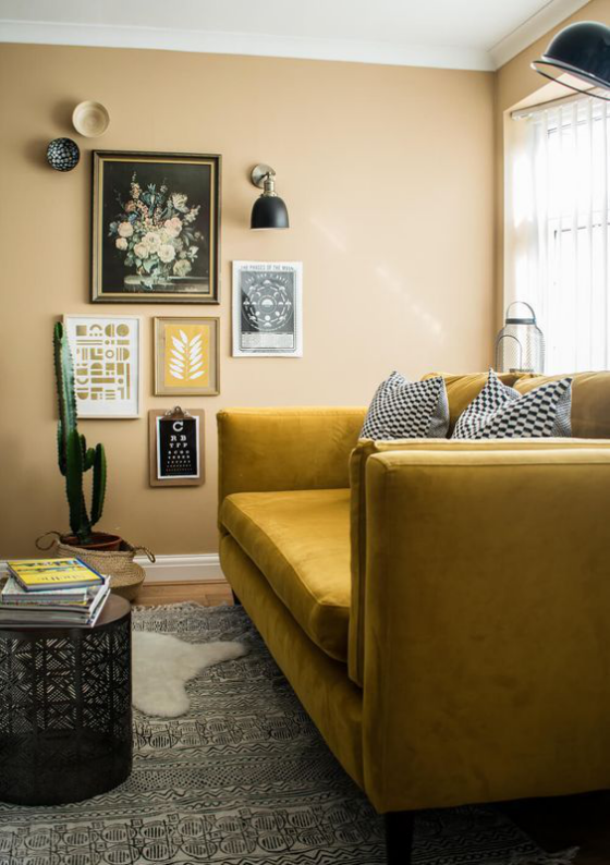 Gelbes Sofa in Goldgelb schickes warmes Interieur graue Akzente Kissen Teppich neutrales Beige an der Wand