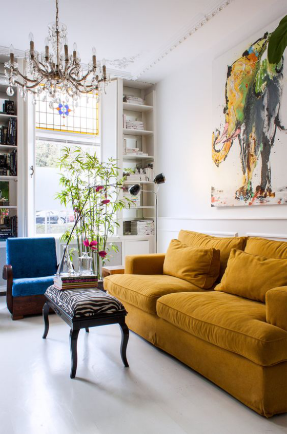 Gelbes Sofa klassisches Raumdesign eklektisch blauer Sessel Wanddeko Kronleuchter