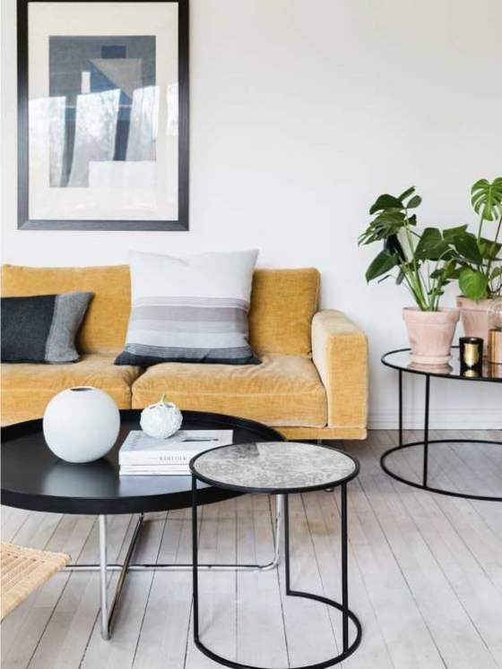 Gelbes Sofa minimalistisch eingerichtetes Wohnzimmer grauer Boden graue Wand Kissen weitere Wohnaccessoires
