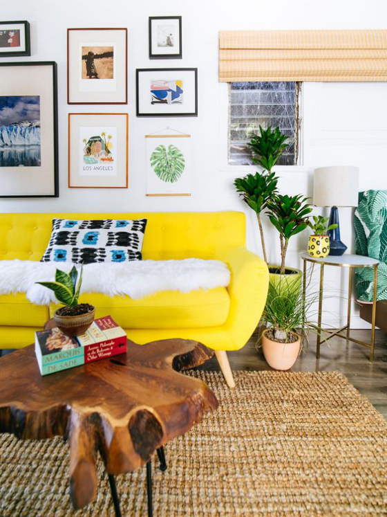 Gelbes Sofa sonnengelbe Nuance Blickfang Holztisch Teppich Wandbilder grüne Pflanzen