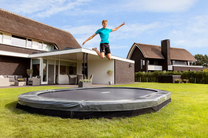 Trampolin Bodentrampolin im Outdoor Bereich junger Mann Sport treiben im eigenen Garten