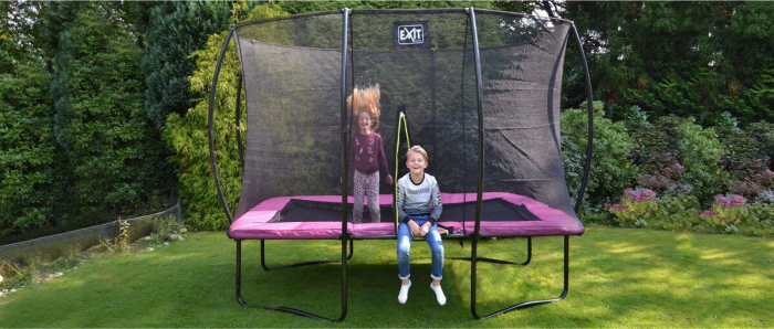 Trampolin im Garten rechteckige Form Sicherheitsnetz zwei fröhliche Kinder beim Spielen