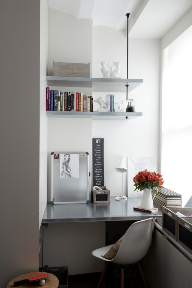 Kleines Home Office am Fenster offene Regale Bücher auf dem Schreibtisch weiße Vase mit farbenfrohen Blumen