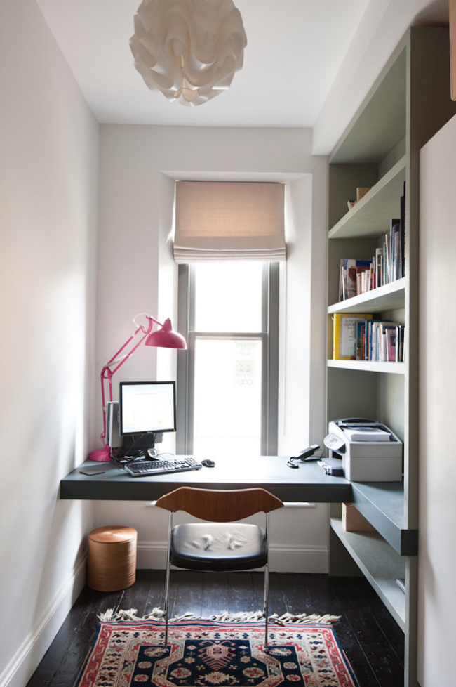 Kleines Home Office einfache Einrichtung im schmalen Raum Schreibtisch direkt vor dem Fenster Lampe PC Teppich rechts Regal