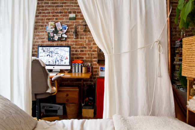 Kleines Home Office im Schlafzimmer hinter weißen Gardinen Ziegelwand schöne Einrichtung