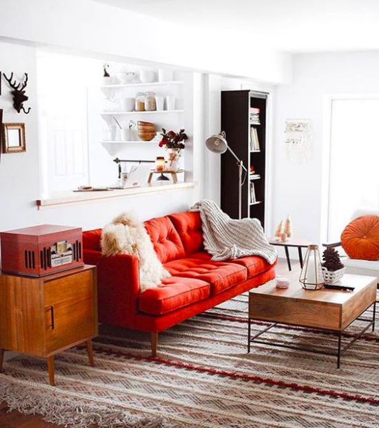 Rotes Sofa als Blickfang heller Teppich Retro Möbel weiße Wände helle Wurfdecken
