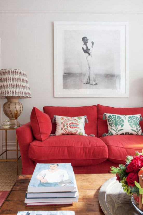 Rotes Sofa als Highlight Kissen Wandbild weiße Wände Bildrahmen Kaffeetisch Bücher