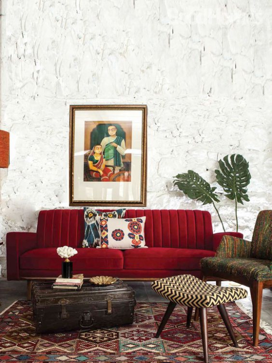 Rotes Sofa buntes Ambiente gemusterter Teppich Weinrot dominiert Deko Kissen Wandbild Retro Stil Koffer als Tisch