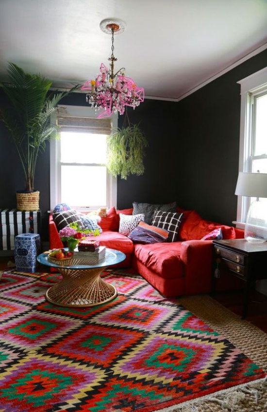 Rotes Sofa farbenfrohes Ambiente bunter Teppich Kissen Palme am Fenster dunkle Wände