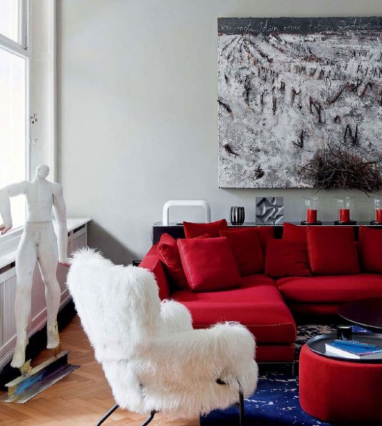 Rotes Sofa fröhliches Ambiente weiße Männerstatue weißer Sesselüberzug Wandbild blauer Teppich