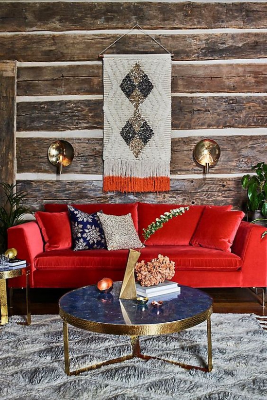Rotes Sofa interessantes Ambiente Goldakzente Holzwand Makramee kleiner runder Tisch grauer Teppich