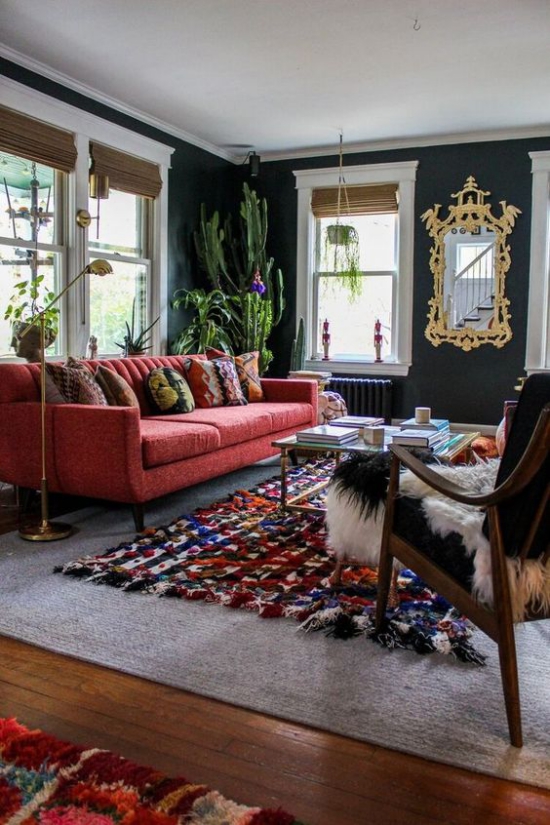 Rotes Sofa klassisches Raumdesign Tufting Teppich dunkle Wände viele Zimmerpflanzen Sessel im Vordergrund