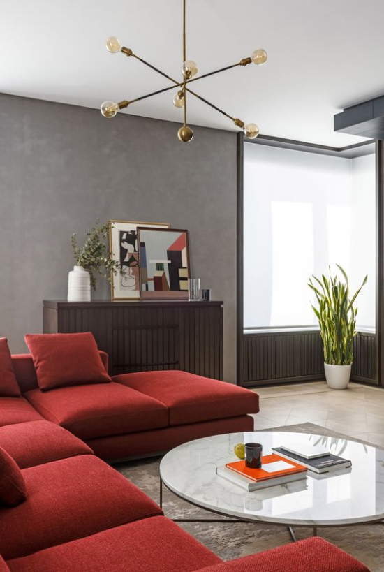 Rotes Sofa klassisches Raumdesign sehr stilvoll graue Wände Fenster Topfpflanze runder Kaffeetisch
