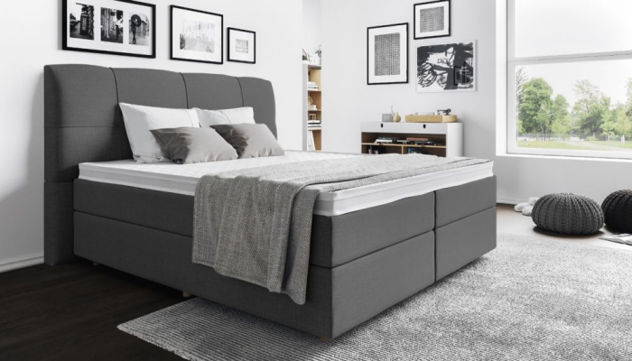 Springboxbett schönes Schlafzimmer in Grau gestaltet großes Bett mit Bettkopfteil Wandbilder grauer Teppich Fenster rechts