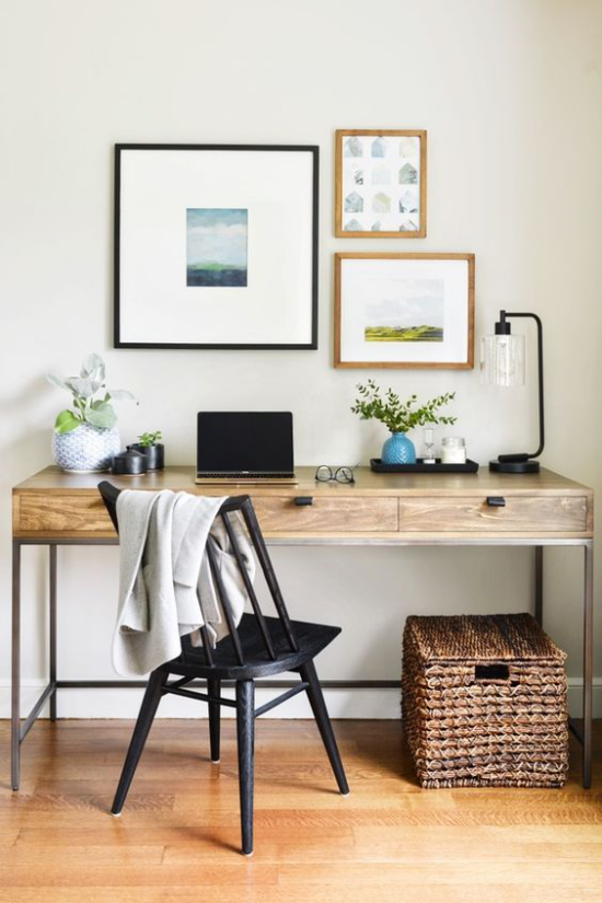 Heimbüro im Landhausstil einfache Einrichtung Schreibtisch aus hellem Holz schwarzer Stuhl drei schöne Wandbilder tolle Dekoration