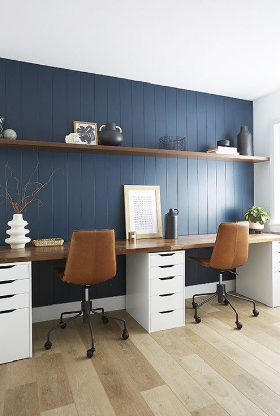 Heimbüro im Landhausstil marineblaue Akzentwand aus Holz Farbakzent braune Lederstühle Arbeitsplatte aus Holz weiße Unterschränke