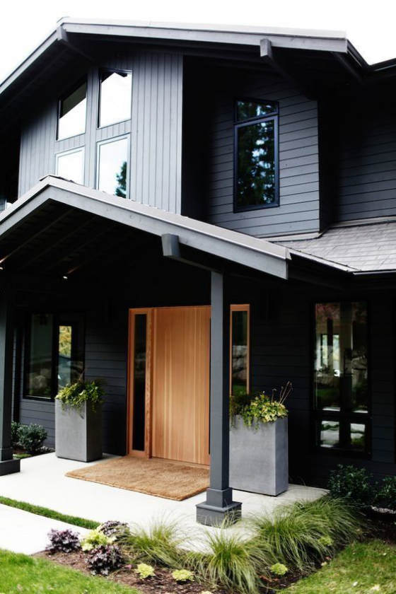 moderne Haustür aus Holz mit zwei Seitenfenstern und schön dekorierter Eingangsbereich 