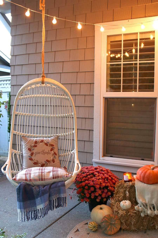 Herbstdeko vor der Haustur auf der Veranda Schaukel romantische Atmosphare ringsum Blumen Kurbisse Leuchtkette