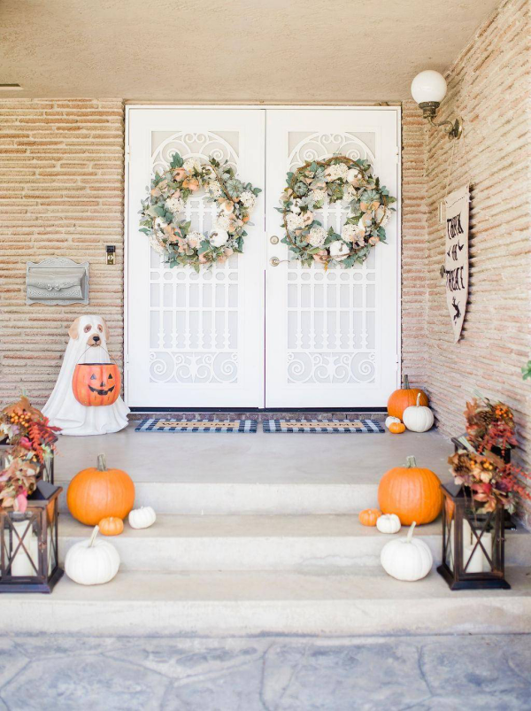 Herbstdeko vor der Haustur schlicht dekorierter Hauseingang Herbstkranze weise und orangenfarbene Kurbisse Laternen mit weisen Kerzen drin
