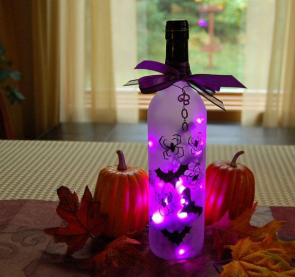 Halloween Deko in Lila dekorierte Weinflasche mit Teelicht schwarze Fledermause Spinnen zwei Kurbisse daneben