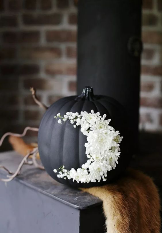 Halloween Deko mit Kurbissen groser schwarzer Kurbis mit weisen Chrysanthemen geschmuckt