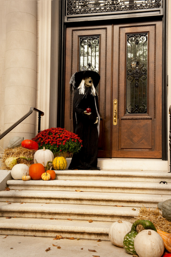 Halloween Deko mit Kurbissen vor der Haustur auf den Treppen rote Chrysanthemen eine