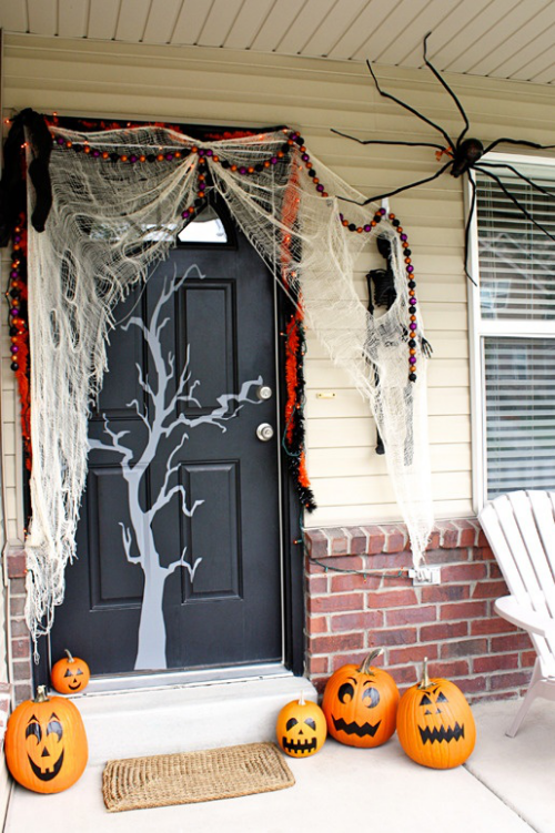 Halloween Deko vor der Haustur schwarze Tur Spinnennetz orangefarbene Kurbisse furchterregend