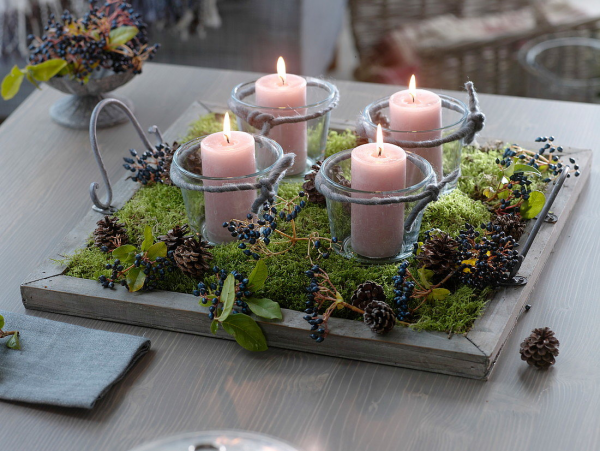 Adventskranz ein Must have der Vorweihnachtszeit auf einem Tablett Moos blaue Beeren vier Kerzen in Glasgefasen