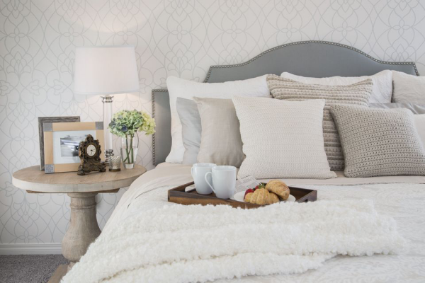 Schlafzimmer zum Wohlfuhlen bequemes Bett Decke Kissen in hellen Farben Tablett Fruhstuck im Bett