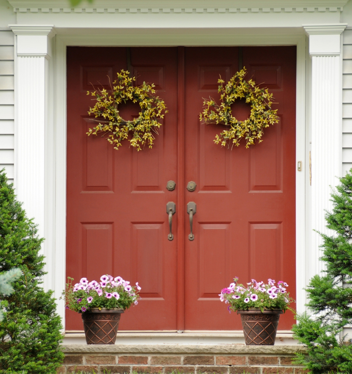 zwei Türkränze und zwei Topfpflanzen als Schmuck vor der Tür