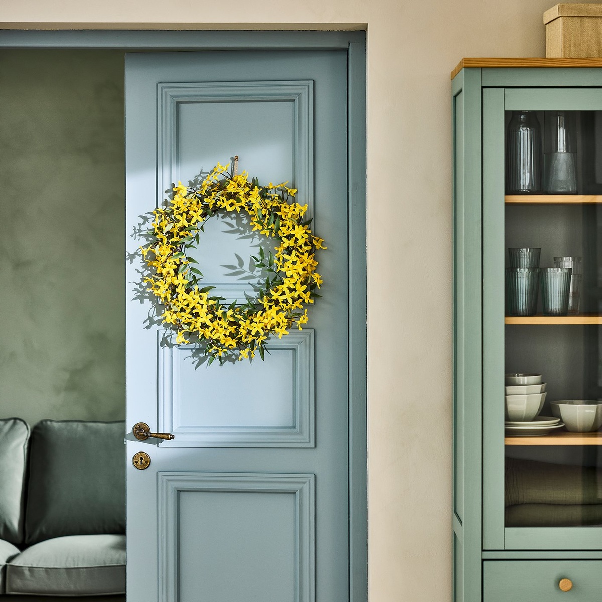 ein Kranz aus Forsythien Zweigen hängt an der Tür