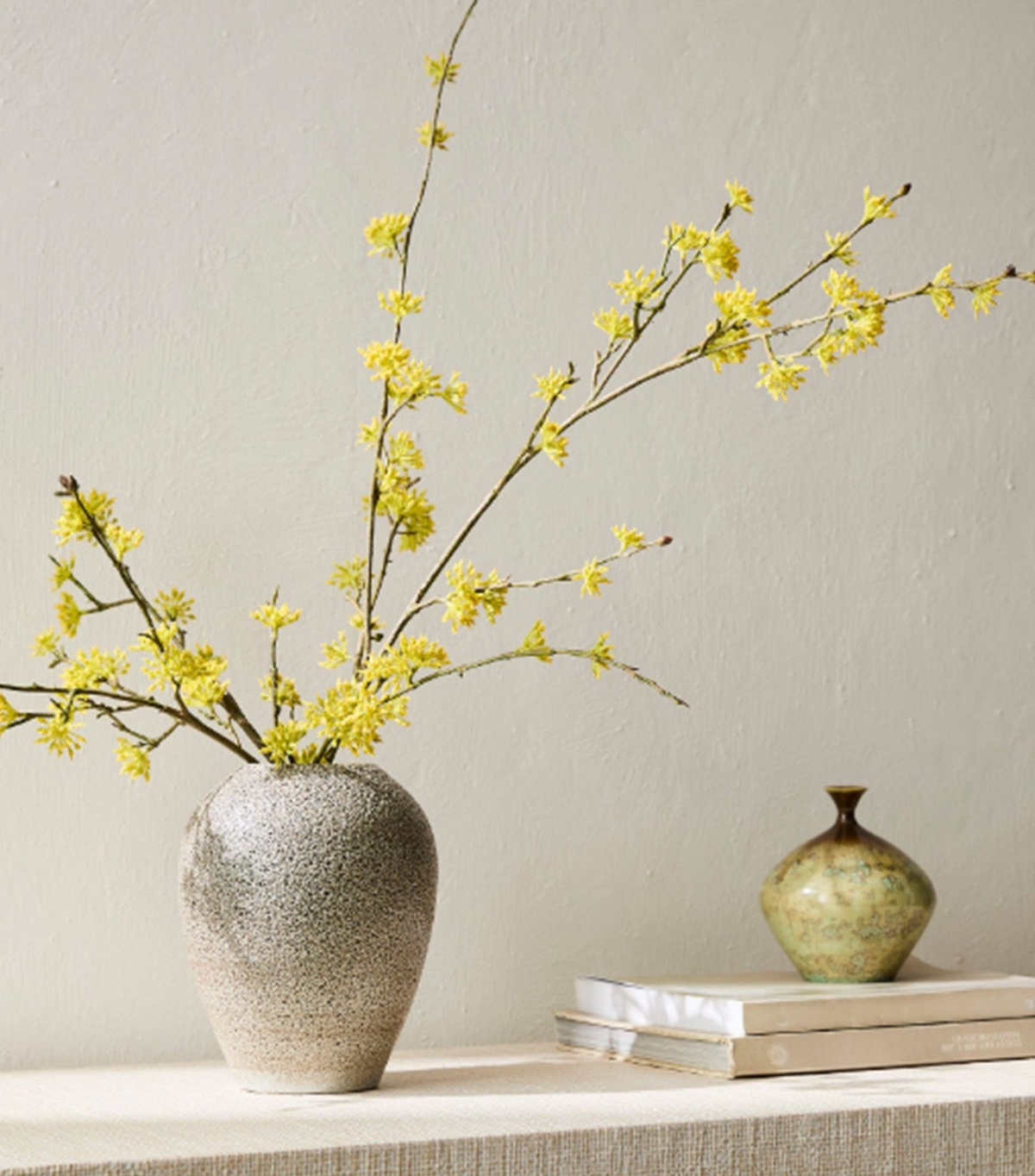 Vase mit Forsythien Zweige auf einem Sims 