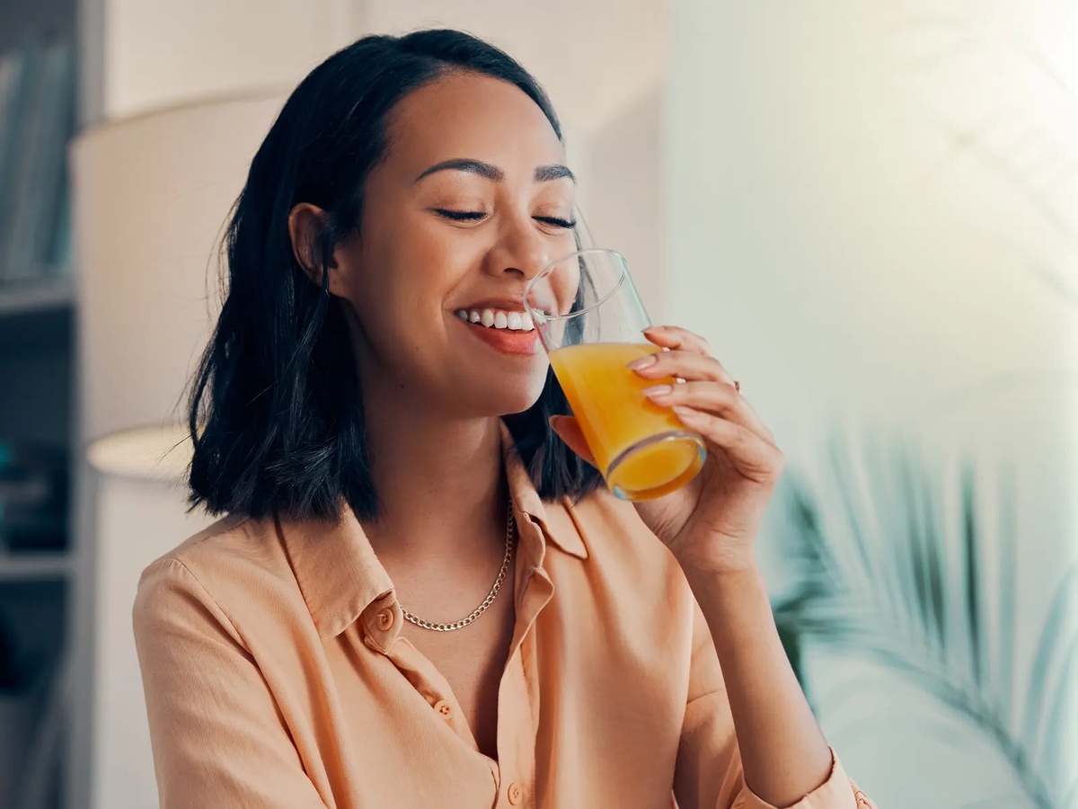 junge Frau trinkt ein Glas frisch gepressten Orangensaft